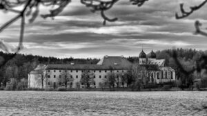 Bild auf den Klosterbau mit der Klosterkirche mit Türmen über den See in schwarz-weiß.